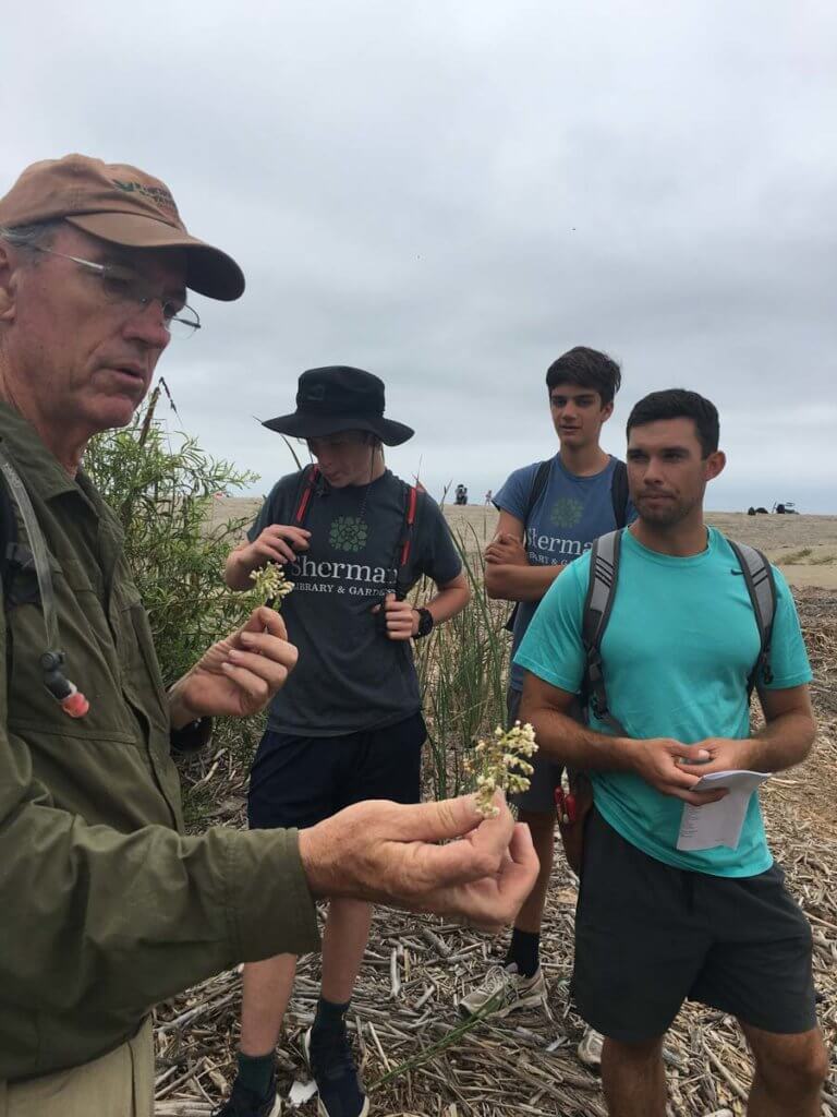 man showing flower to high school students