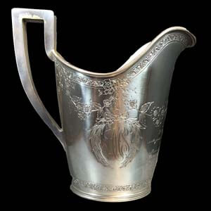 a sliver pitcher decorated with engravings