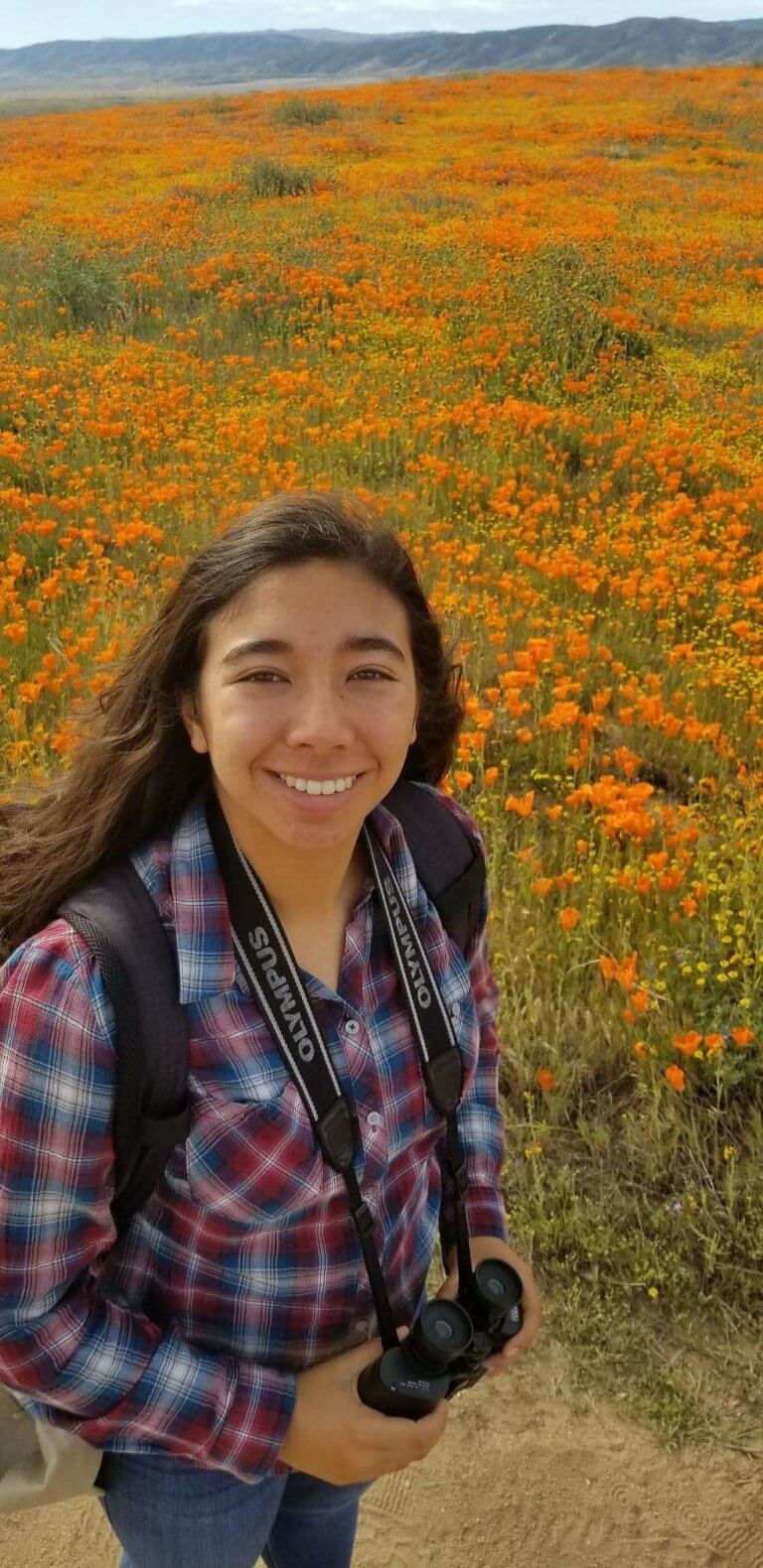 girl smiling in front of field of flowers