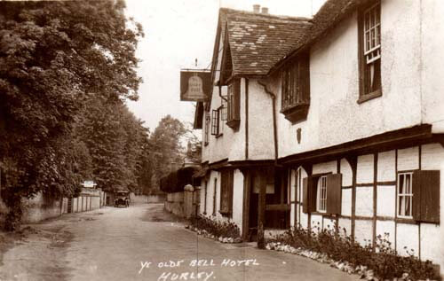 old image of a road with ouses on the right and trees on the left